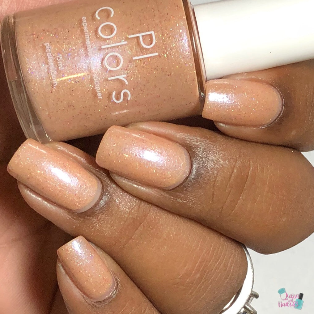 A hand with neatly manicured nails, painted in a shimmering pale orange hue, grips a bottle labeled "PI Colors." This shade, titled "Sunrise Tellin.027," boasts a subtle holographic glitter finish that adds an extra sparkle to the look.