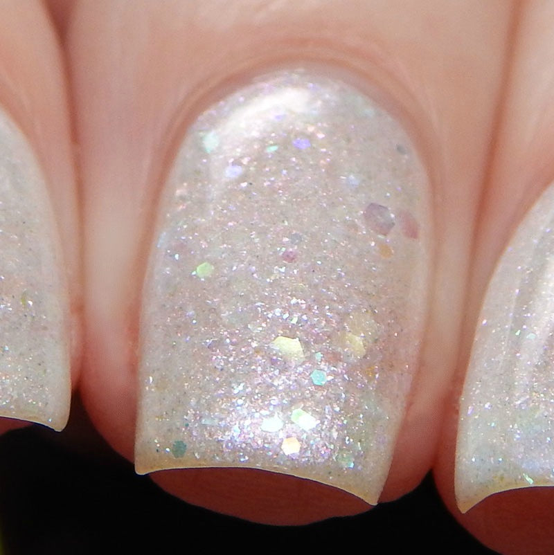 Close-up of fingernails painted with PI Colors' Troth of Innocence.001 White Nail Polish, featuring a shimmery, iridescent finish with small multicolored glitter and iridescent flakes. The nails are neatly manicured and have a glossy finish.