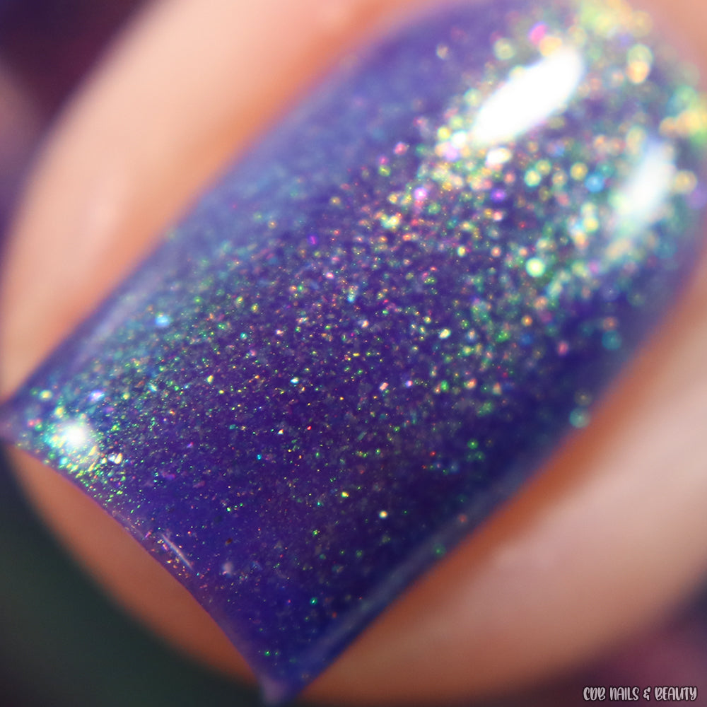 Close-up of a nail coated with PI Colors' 90s Kind of World Purple Nail Polish, showcasing multicolored sparkles and a glossy finish. The vibrant hues create a shimmering, magical effect.