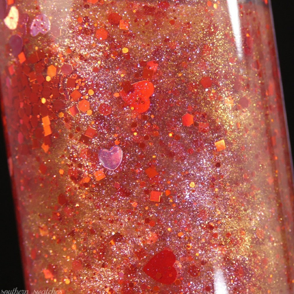 Experience a close-up of the mesmerizing Strawberry Heart.208 Red Nail Polish Topper from PI Colors, featuring shimmering golden glitter and holographic, heart-shaped specks. This 10-free nail polish offers a sparkling iridescence with glitter particles in various sizes.