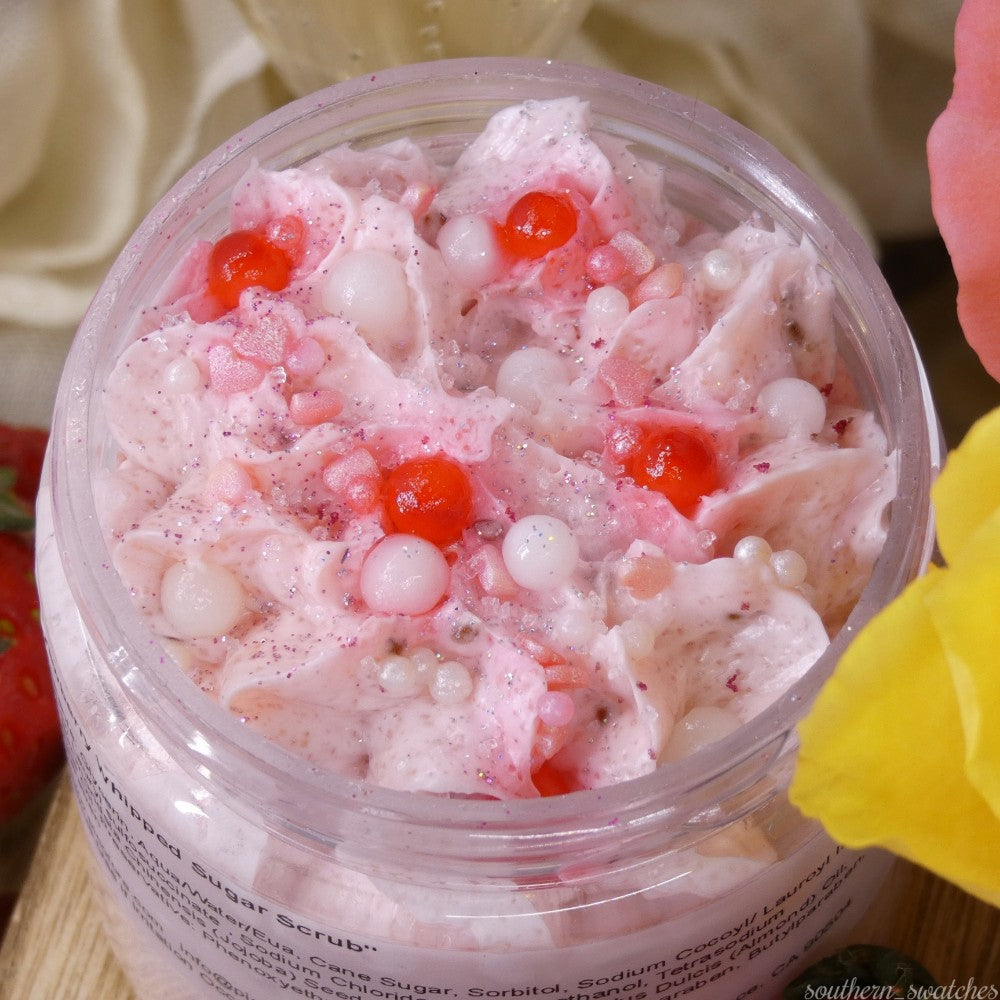 The Strawberry Whipped Soap Sugar Scrub by PI Colors features a creamy pink texture adorned with red and pearlescent beads. This luxurious scrub is infused with avocado oil and decorated with shimmering glitter.