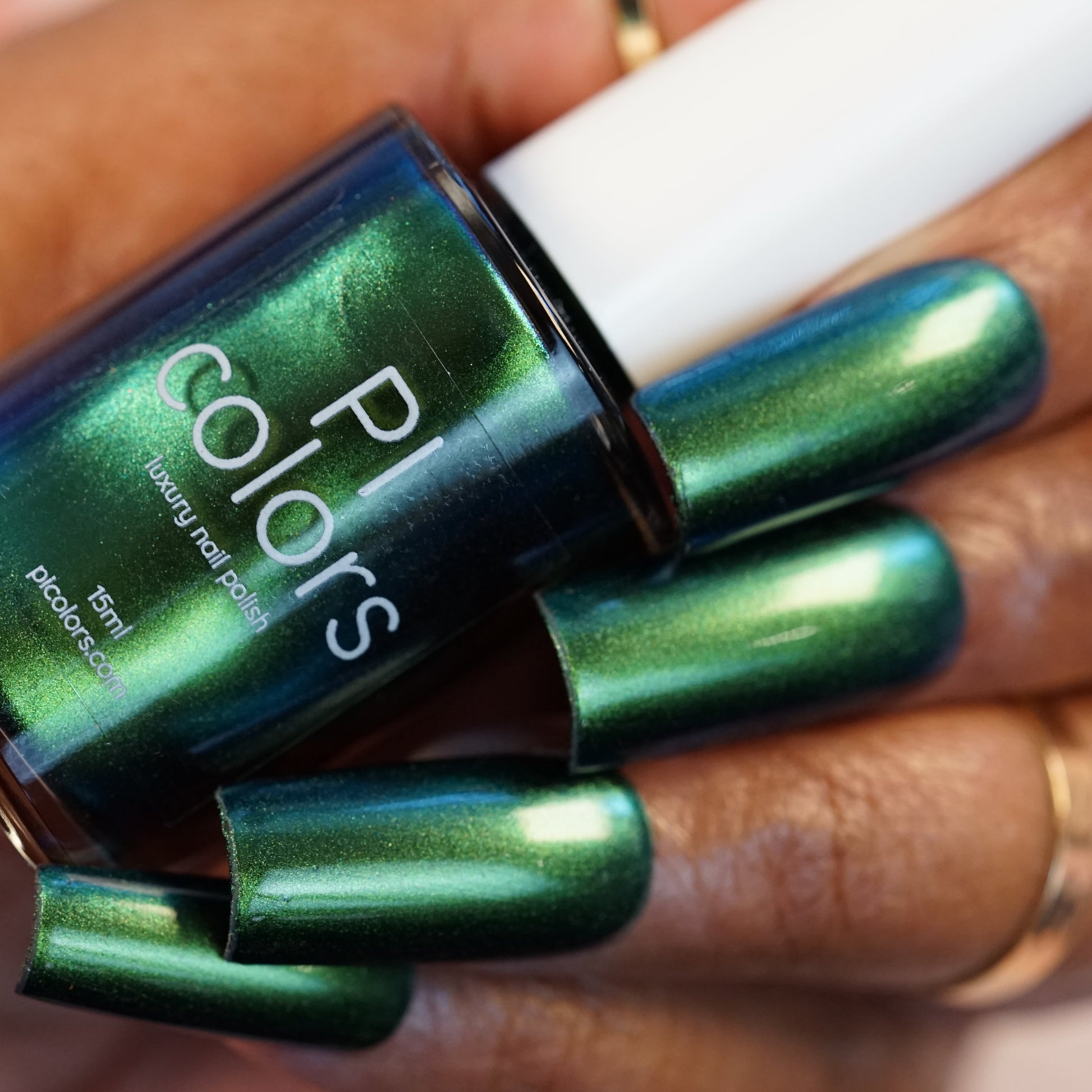 A hand adorned with Green Glow.209 nail polish in forest green metallic pairs perfectly with a matching bottle labeled "PI Colors, Green Glow.209, 15ml." The long, oval-shaped nails reflect light beautifully with a shiny finish.