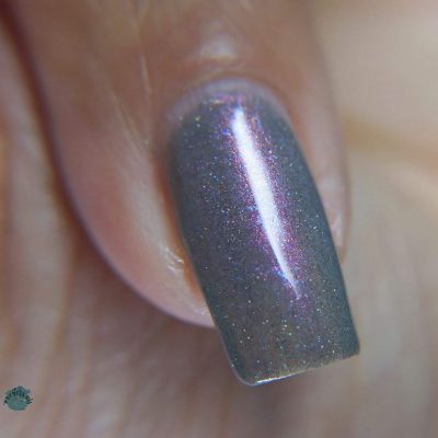 Close-up of a single fingernail adorned with PI Colors' Cirrus.118 Pink Gray Nail Polish, its purple shimmer catching light in a vertical stripe.