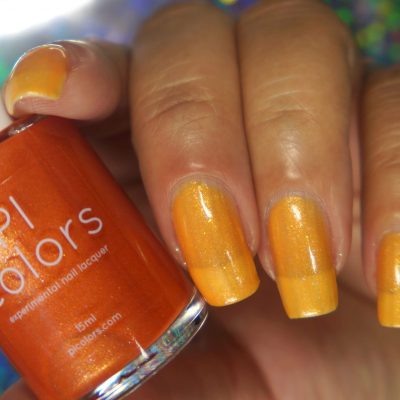 A hand showcases manicured nails painted in a glossy, shimmery shade of orange-yellow using the "Sun Conure.097 Orange Nail Polish." Next to the hand is an orange bottle labeled with "PI Colors," a brand renowned for its luxury nail lacquers. The background is artistically blurred with a blend of colors, emphasizing the vibrance of this premium 10-free polish.