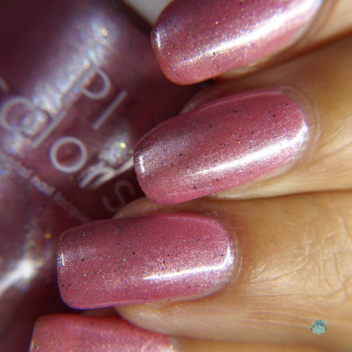 Close-up of a hand with neatly manicured nails painted with PI Colors' Roseate Bliss.012 Pink Nail Polish. The glossy finish is enhanced by holographic glitters, adding dimension. In the background, a partially visible bottle of matching 10-free polish completes the chic look.