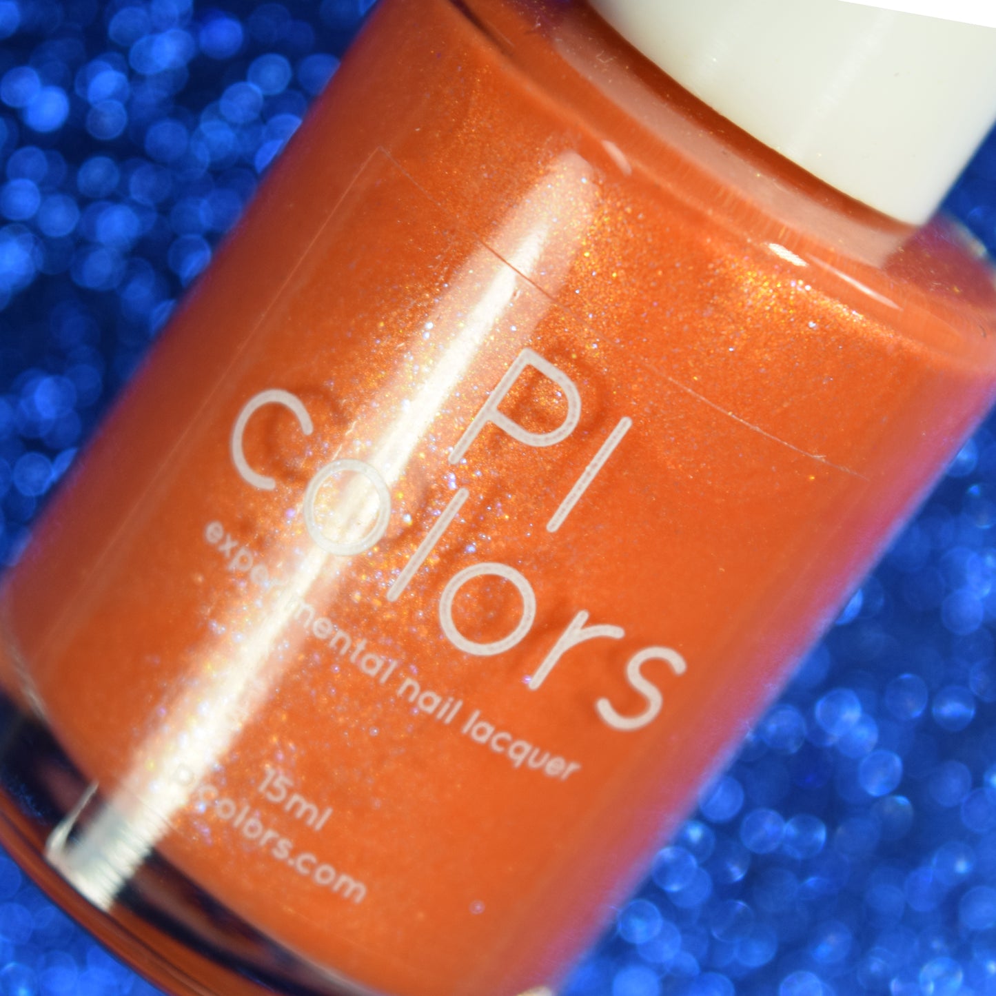 A bottle of "Sun Conure.097 Orange Nail Polish" by PI Colors, celebrating a luxurious 10-free formula with a glistening finish. The backdrop features an out-of-focus, shimmering blue texture, adding vibrant contrast to the glossy bottle.