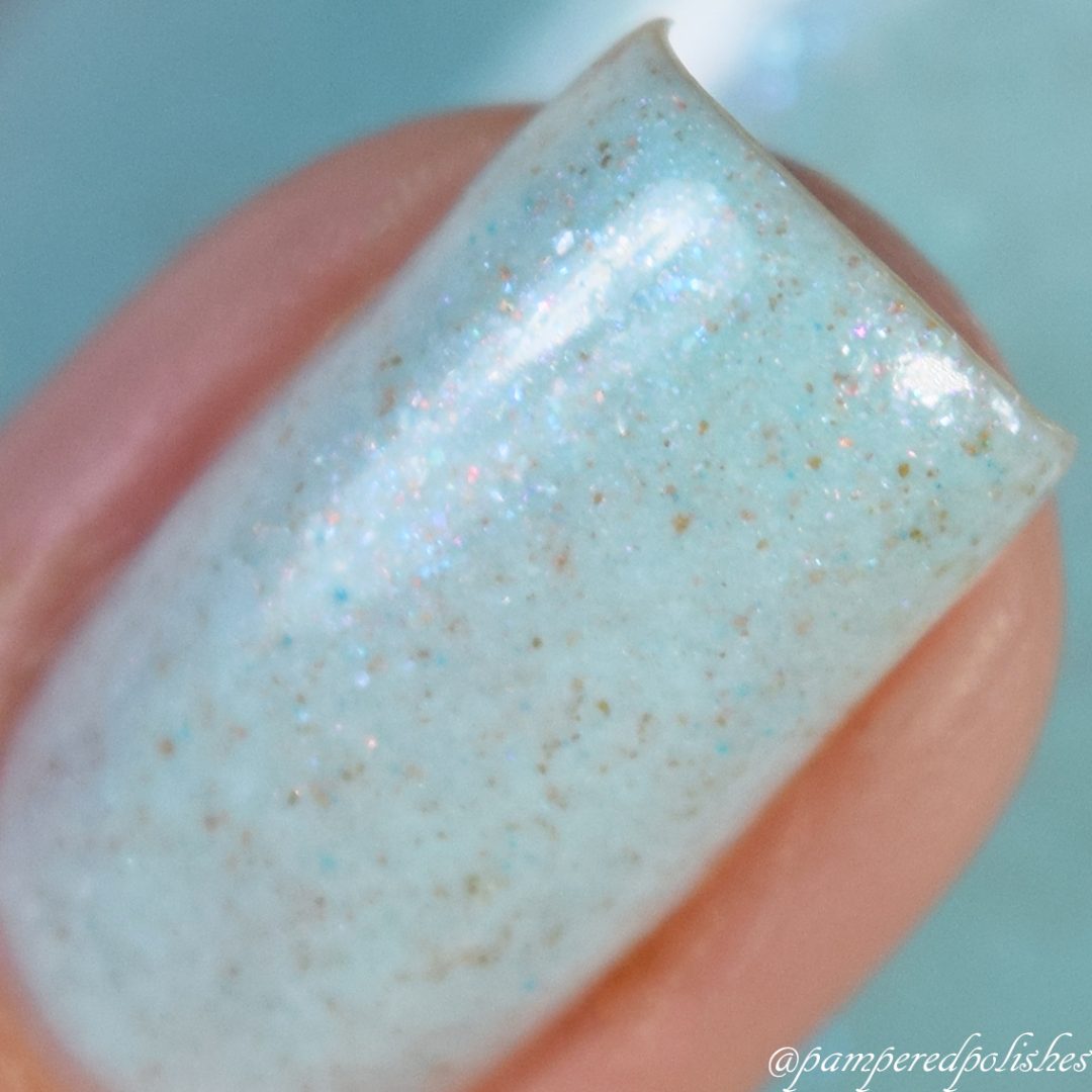 A close-up of a fingernail painted with Marshmellow Dream.001, a pale green nail polish from PI Colors. It features a shimmery, glittery finish that captivates with its glossy surface and subtle sparkle.