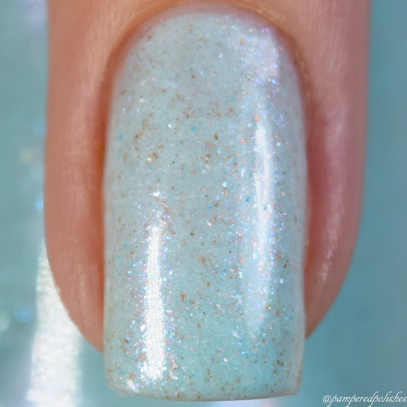 Close-up of a fingernail painted with Marshmellow Dream.001, a pale green shade from PI Colors, showcasing subtle speckles and a shimmering finish. The nail is neatly manicured against a blurred background.