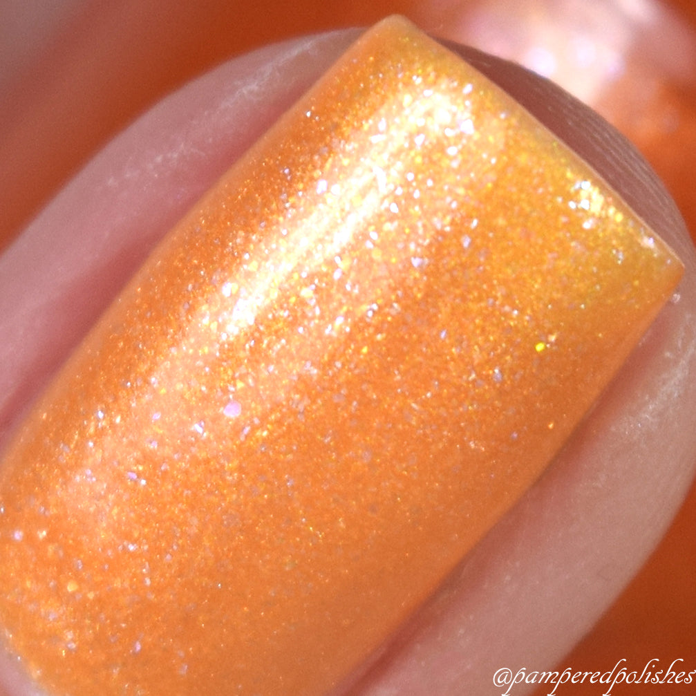 Close-up of a fingernail adorned with PI Colors' Sun Conure.097 Orange Nail Polish, featuring a smooth, glossy finish with subtle sparkles. The background is blurred, emphasizing the vivid color and texture of this 10-free lacquer.