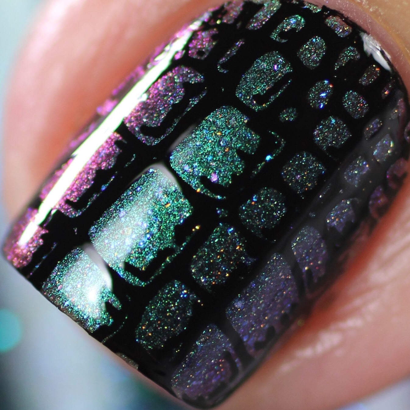 The image highlights a manicure using PI Colors' Formalhaut.036 Green Black Nail Polish, featuring a glittery multicolor base with hues of green, purple, and pink. It is adorned with a black geometric crackle pattern and enhanced by holographic glitter for an eye-catching shine that sparkles with every movement.
