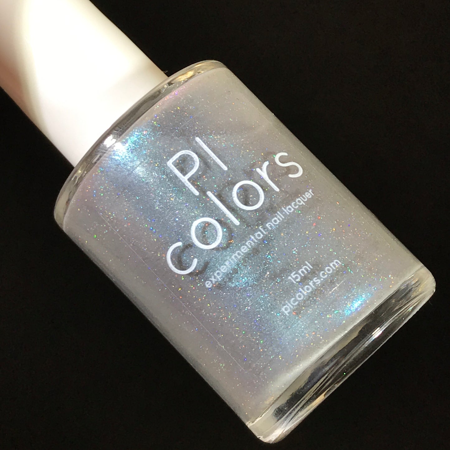 A bottle of PI Colors nail lacquer, Asperitas.105 Blue Gray Nail Polish, is shown against a black background. The handmade polish shimmers in a translucent shade with holographic sparkle, and the label reads "PI Colors, experimental nail lacquer, 15ml, picolors.com".
