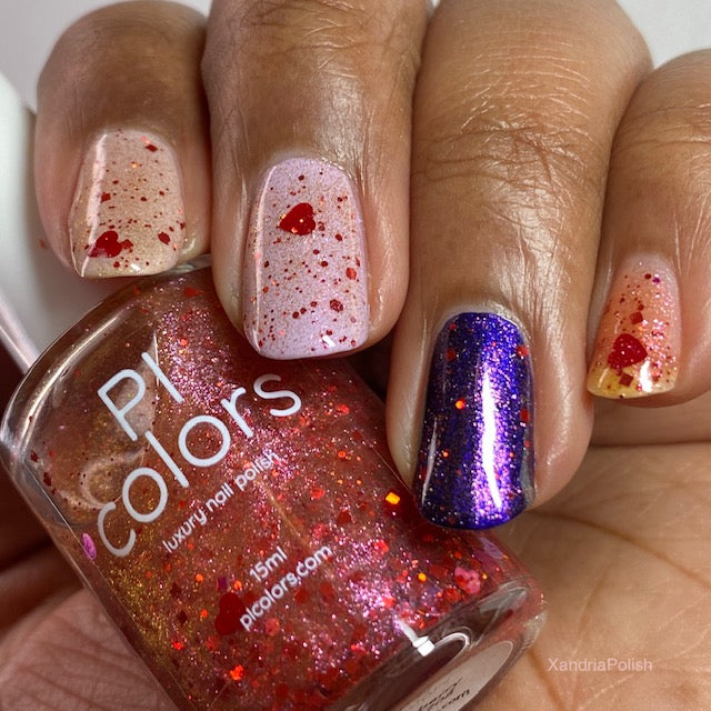 A hand presents nails featuring various designs: two nails sport a clear base adorned with red heart and glitter details, highlighted by holographic heart accents. Another nail shines with purple glitter, while the thumb is decorated with red and gold glitter. The hand holds a bottle of PI Colors' Strawberry Heart.208 Red Nail Polish Topper, which is 10-free.