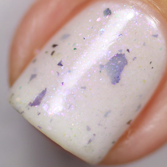 Detailed view of a fingernail adorned with PI Colors' Azarath.000 White Nail Polish, showcasing iridescent aurora shimmer and small chameleon flakes, resulting in a captivating, shimmering effect.