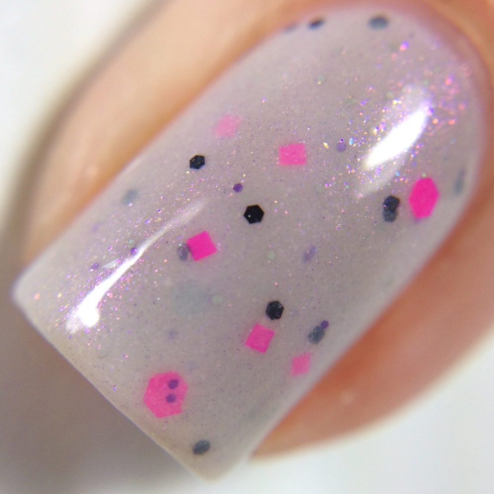 Close-up of a fingernail adorned with Kirin.000 Lilac Purple Nail Polish by PI Colors, showcasing light pink glitter along with black, pink, and blue multicolored hexagonal and square confetti. The background is softly blurred.
