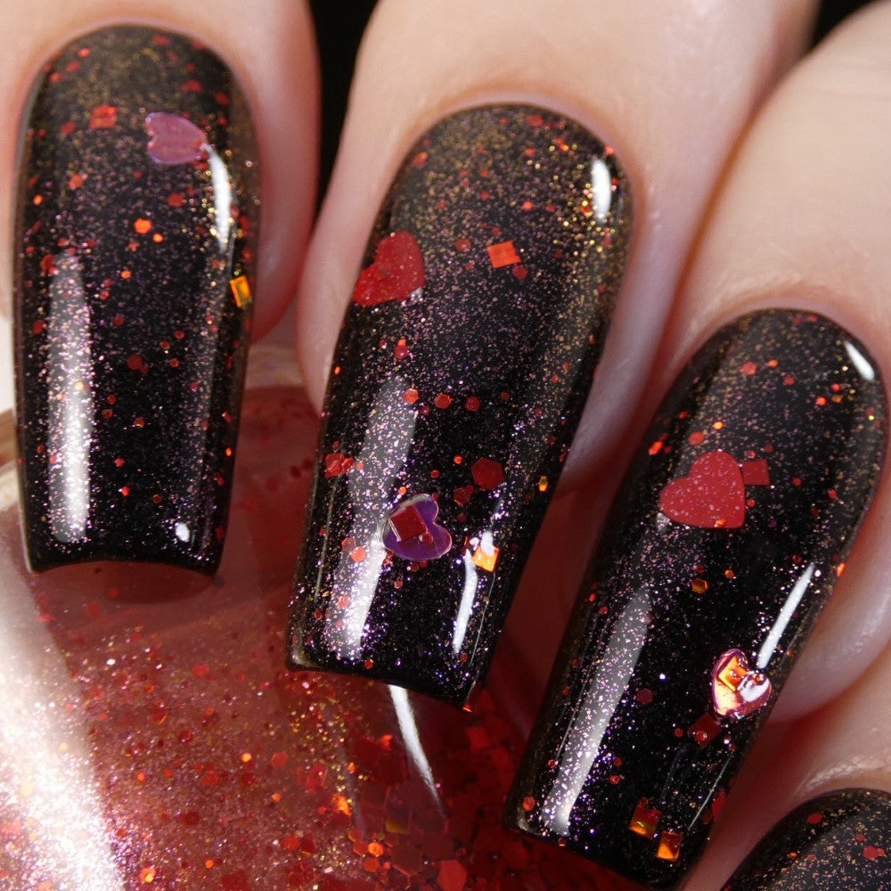 Close-up of fingernails adorned with PI Colors' Strawberry Heart.208 Red Nail Polish Topper, showcasing a 10-free black base infused with red glitter and holographic heart-shaped accents. The nails catch the light, accentuating the intricate design and glossy finish.