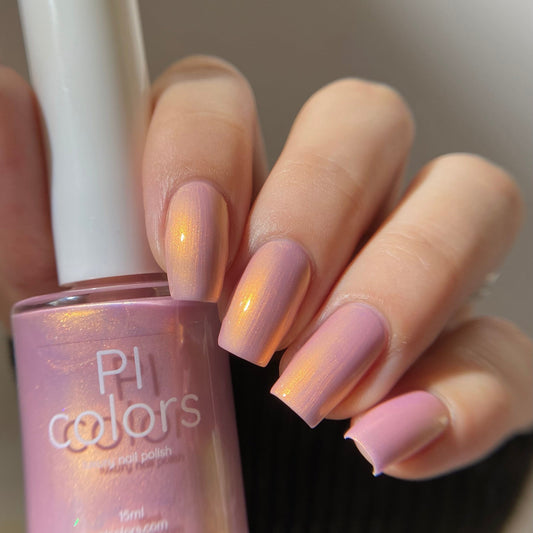 Hand holding a bottle of PI Colors nail polish with matching pink nails.