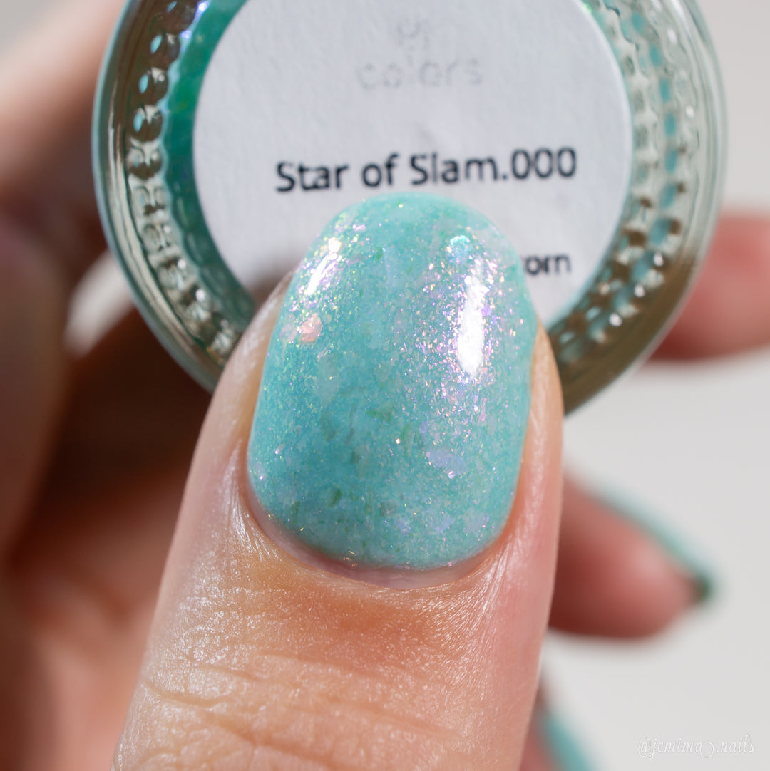Close-up of a fingernail painted with pastel teal nail polish, adorned with pink and white sparkles. The background showcases a bottle labeled "Star of Siam.000" by PI Colors, highlighting its 10-free formula and colorshifting rainbow flakies for a magical touch.