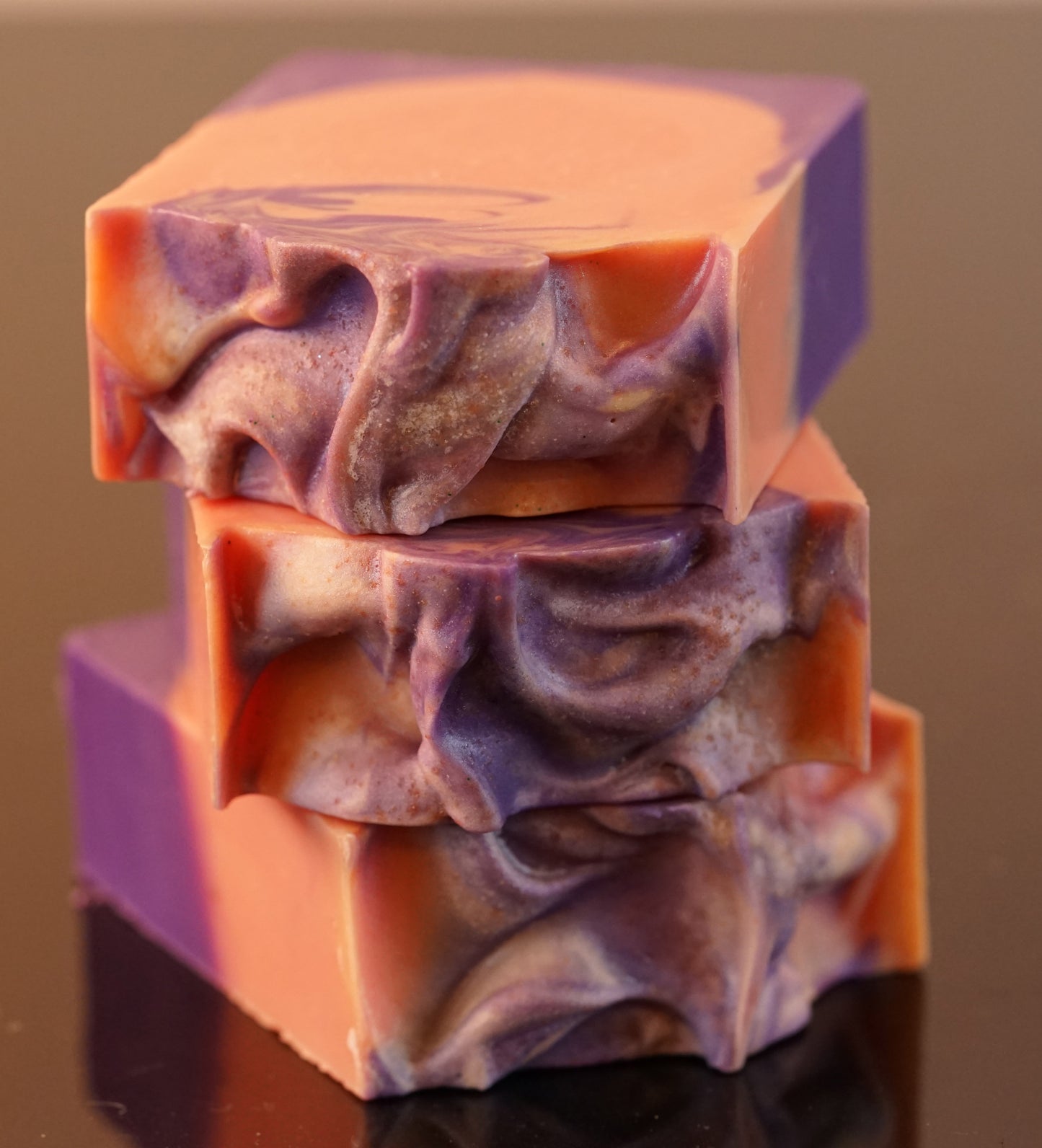 Three PI Colors Autumn Moon Artisan Soap Bars are stacked, displaying marbled swirls in vibrant purple, pink, and spiced orange. The glossy surface of natural ingredients highlights intricate patterns and textures.