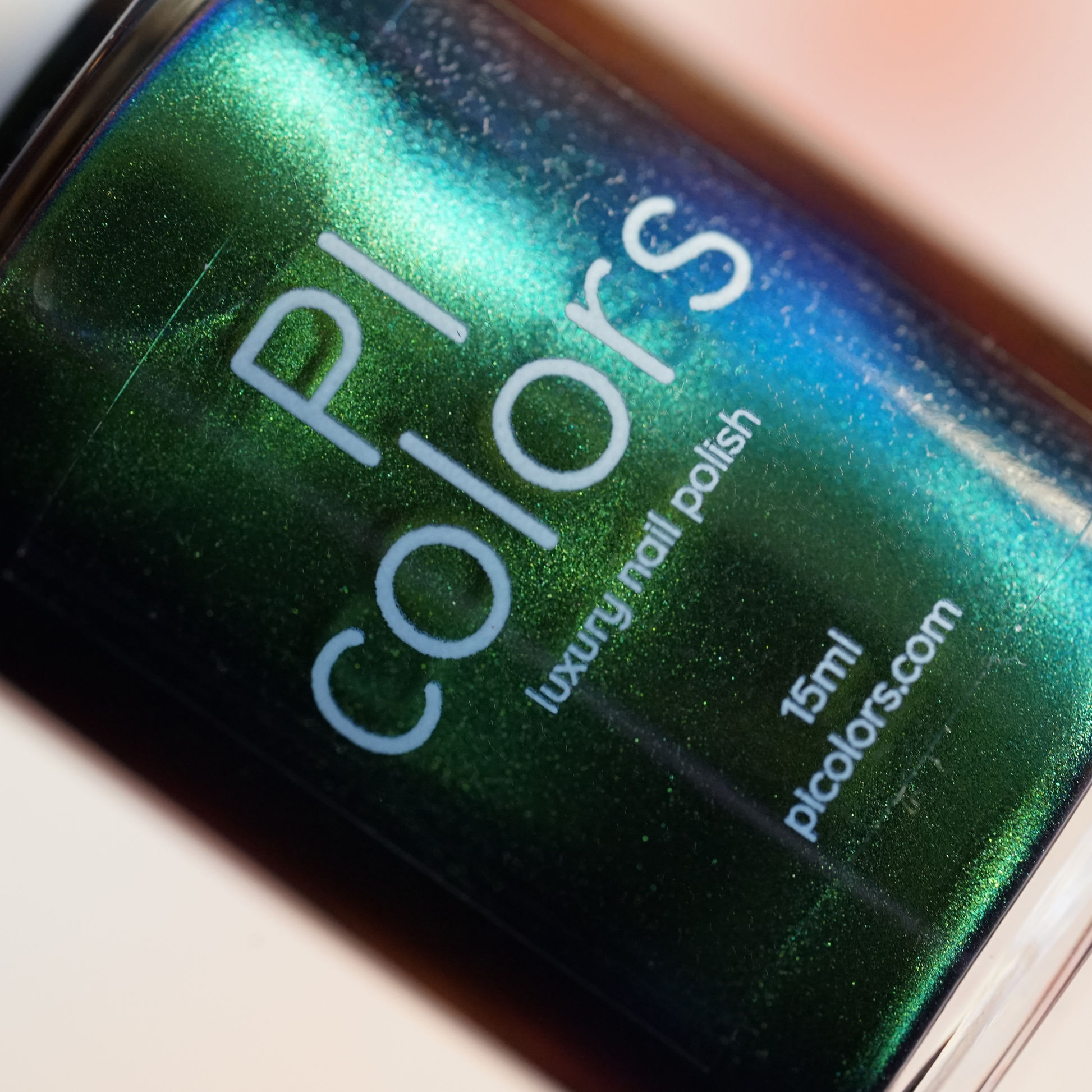 Close-up of a "PI Colors" bottle showcasing a luxury nail lacquer named "Green Glow.209," featuring a shimmering forest green hue with hints of blue. The label reads "multichrome nail polish," offering 15 ml of opulence at picolors.com. The bottle is artfully tilted against a neutral backdrop.