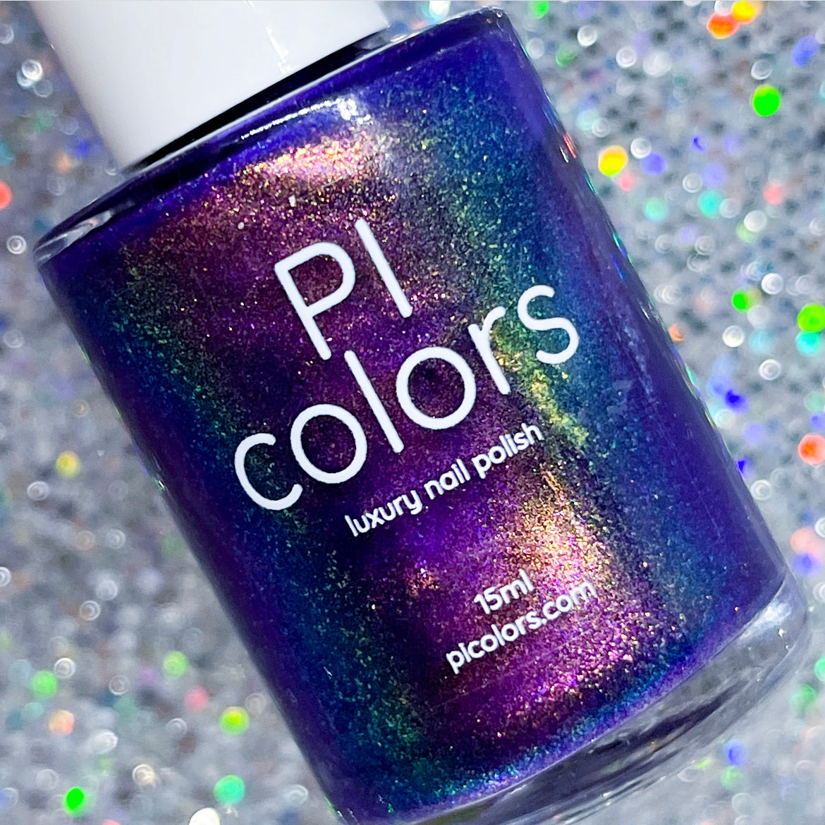 A bottle of PI Colors' 90s Kind of World Purple Nail Polish gleams on a sparkling, glittery background. This handmade nail polish features a vibrant, iridescent sheen with shades of violet purple, blue, and green due to its aurora pigment. It contains 15ml of product and is available at pIcolors.com.
