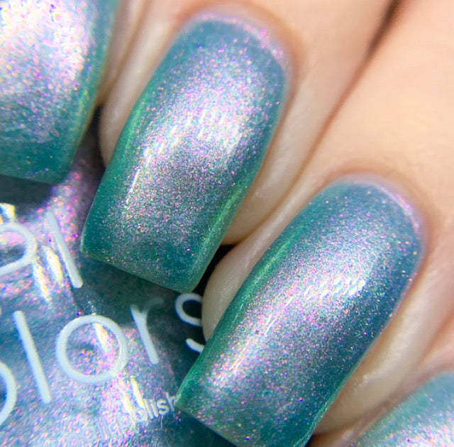 A close-up of nails painted with PI Colors' Ocean Whitecap.309 Blue Nail Polish, featuring a shimmering blue-green hue with a subtle pink iridescent effect and color-changing properties. The neatly manicured nails highlight the glossy, reflective finish of this handmade polish.