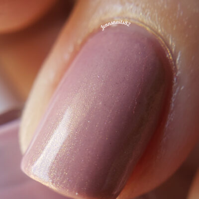 A close-up of a fingernail painted with PI Colors' Milk Berry.073 Pink Nail Polish, showcasing its shimmering dusty pink hue from our luxury nail lacquers collection. The softly blurred background emphasizes the glossy finish and reflective shimmer on the nail surface.