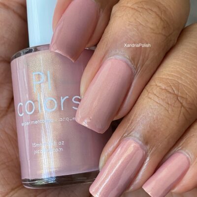 Close-up of a hand with neatly painted nails in a soft pink shade. This luxury nail lacquer, branded as "PI Colors," exemplifies the elegance of Milk Berry.073. The individual is holding the handmade bottle of Milk Berry.073 Pink Nail Polish, perfectly complementing their manicure.