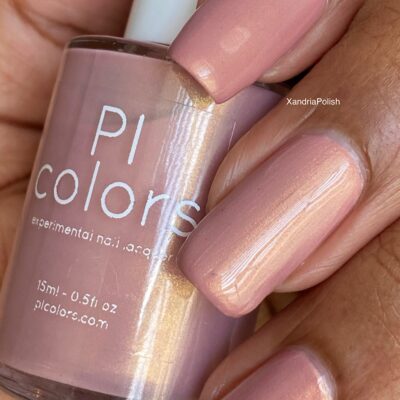 A close-up shot features a hand with neatly manicured nails painted in an elegant, soft pink hue. The hand is holding a bottle of PI Colors' Milk Berry.073 Pink Nail Polish, which precisely matches the nail color. The label displays 15ml/0.51 fl oz and the brand name is prominently shown.
