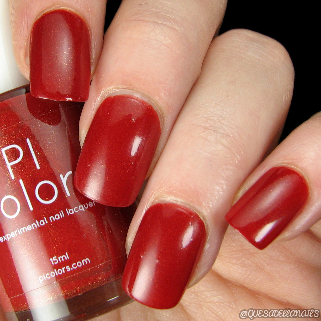 A close-up image features a hand with short, square-shaped nails adorned in a glossy dark red shade from PI Colors' Blood Moon.090 Red Nail Polish, a luxury lacquer that is 10-free for the discerning beauty enthusiast, with the bottle partially visible.