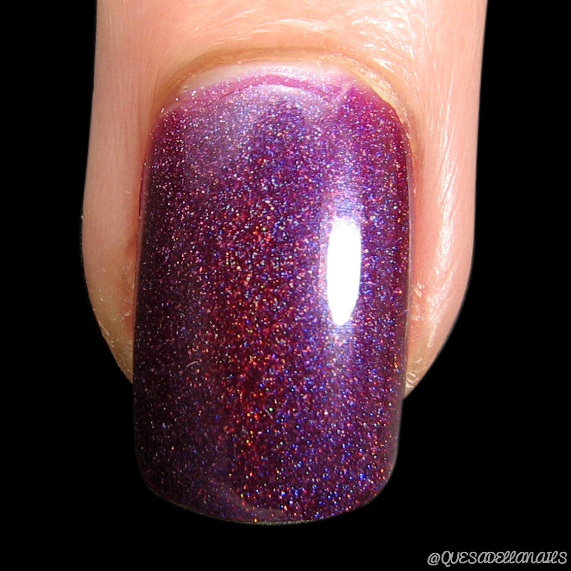 A close-up of a fingernail coated with PI Colors' Castor.011 Red Purple Nail Polish showcases its stunning, shimmering deep red-purple base. The 10-free formula sparkles magnificently, reflecting light through its delicate glittery texture.