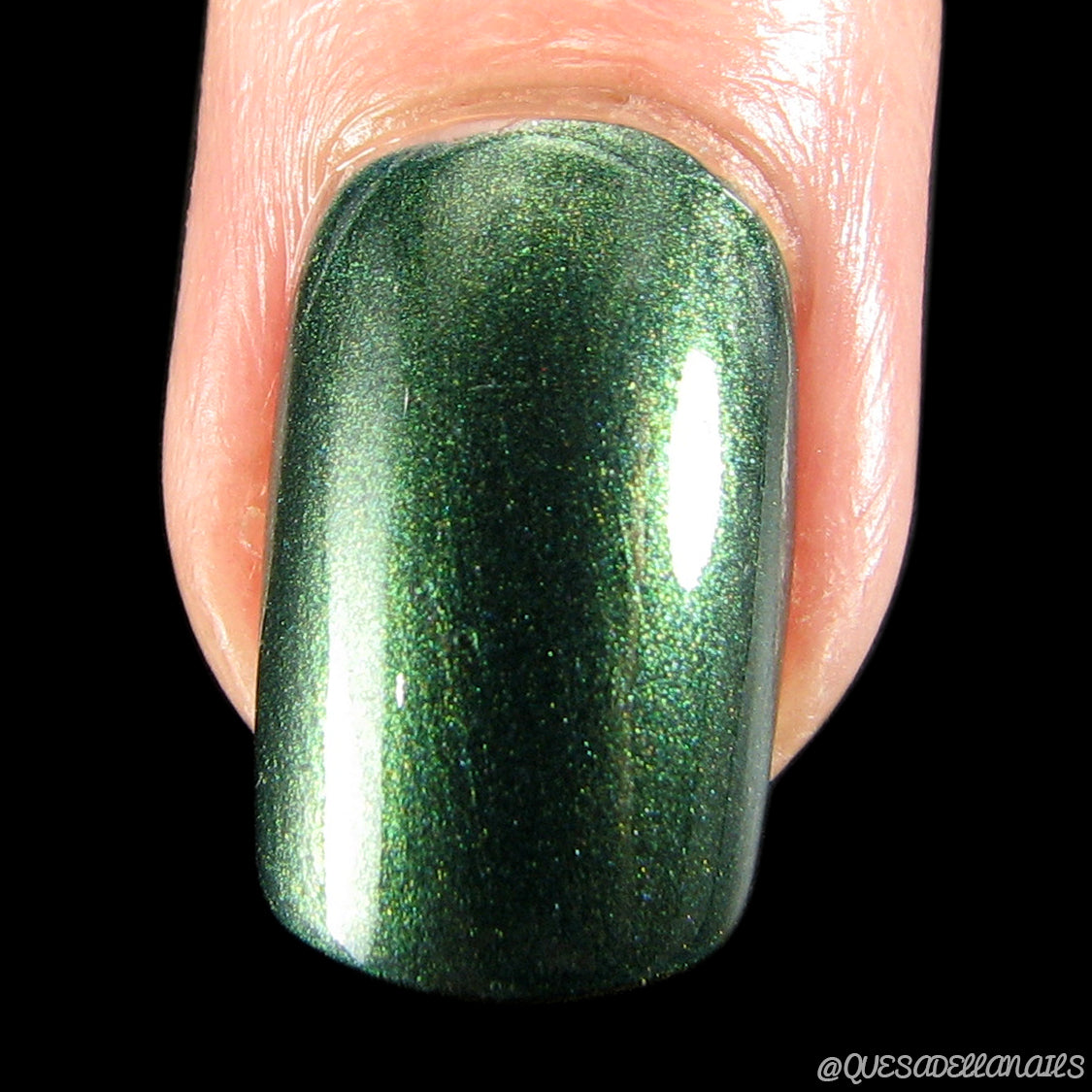 Close-up of a fingernail adorned with PI Colors' Juniper Night.001 Green Nail Polish in a shimmering metallic forest green hue. This 10-free, handmade polish boasts a glossy finish that accentuates the smooth and vibrant color.