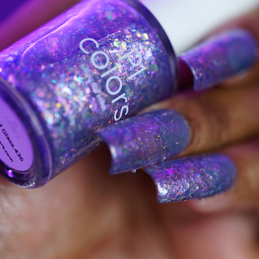A person holding a bottle of PI Colors Stained Glass.436 handmade purple grey nail polish.