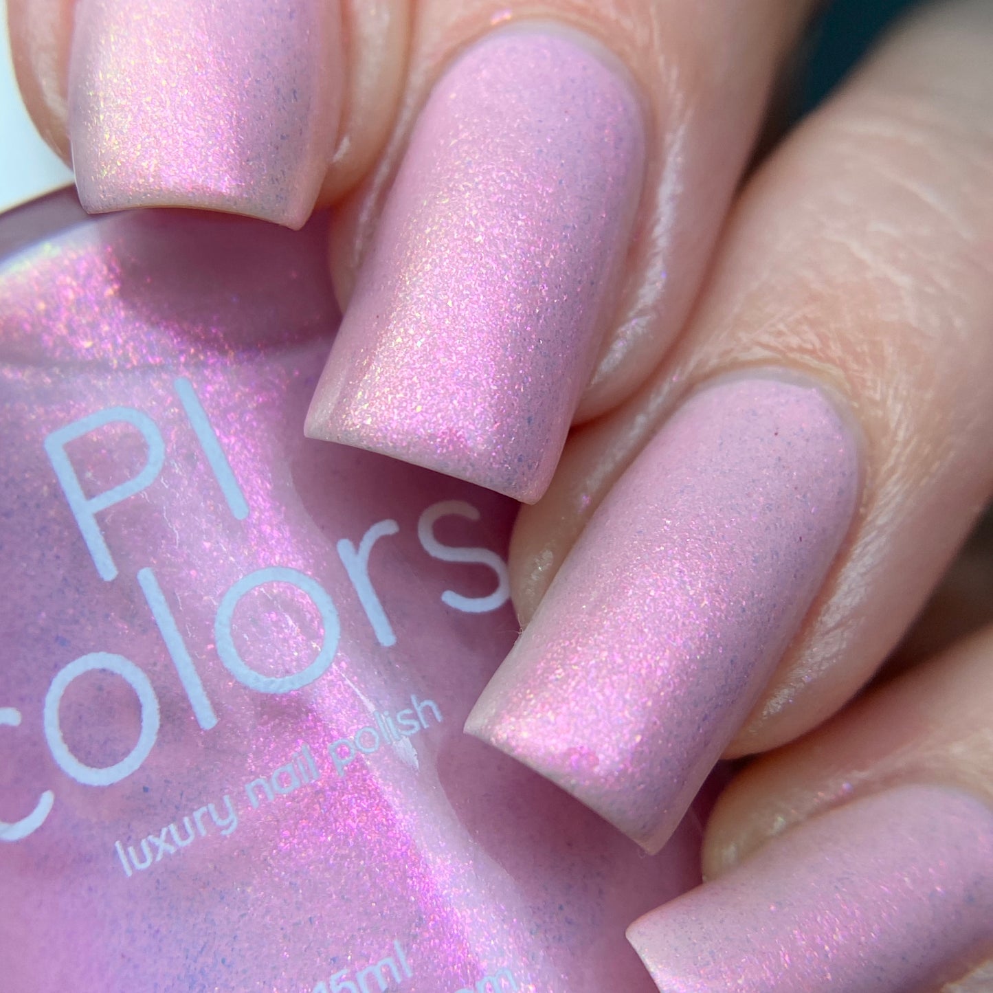 A close-up of fingers featuring nails painted in the Sunset Aurora.322 Pink Nail Polish by PI Colors, a luxury 10-free lacquer. The glossy finish accentuates the smooth application and iridescent sheen of this exquisite handmade polish.