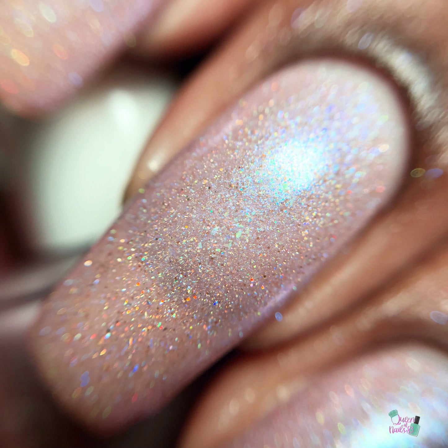 Close-up of a fingernail adorned with Moazagotl.127 Pink Nail Polish by PI Colors, featuring a 10-free formula that offers a pinkish hue and multicolored glitter specks. This combination reflects light to produce a mesmerizing sparkle effect, showcasing the rich texture and dazzling shimmer.