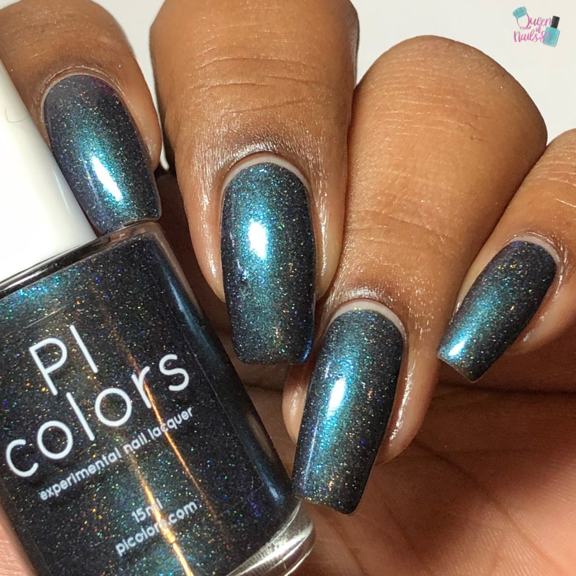 A hand displays nails adorned with a shimmering dark blue-green shade of Noctilucent.111 Black Nail Polish from PI Colors. The bottle indicates it's an experimental nail lacquer that features a luxurious, shiny metallic finish, enhanced with subtle sparkles that captivate the eye.