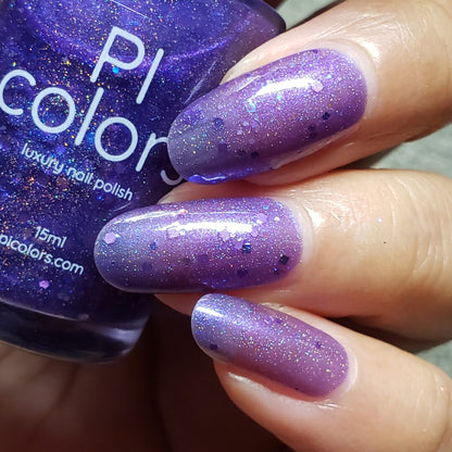 A close-up shows a hand with long nails painted in the sparkling hue of holo purple glitters. Beside them, a bottle labeled "PI Colors Purple Smoke.001 Nail Polish" is visible, reflecting light gracefully. This luxurious purple jelly polish and the nails together create an enchanting, shimmering effect.