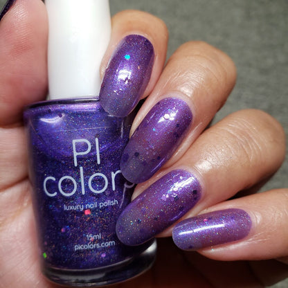 A hand with long nails, coated in a glossy purple jelly polish and sprinkled with tiny holo purple glitters, holds a bottle of "Purple Smoke.001 Purple Nail Polish" by PI Colors.