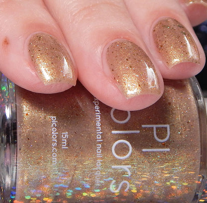 A close-up captures a hand with nails elegantly polished in Golden King.001 Gold Nail Polish. In the foreground, the bottle features the PI Colors brand name along with intricate holographic details on its label.