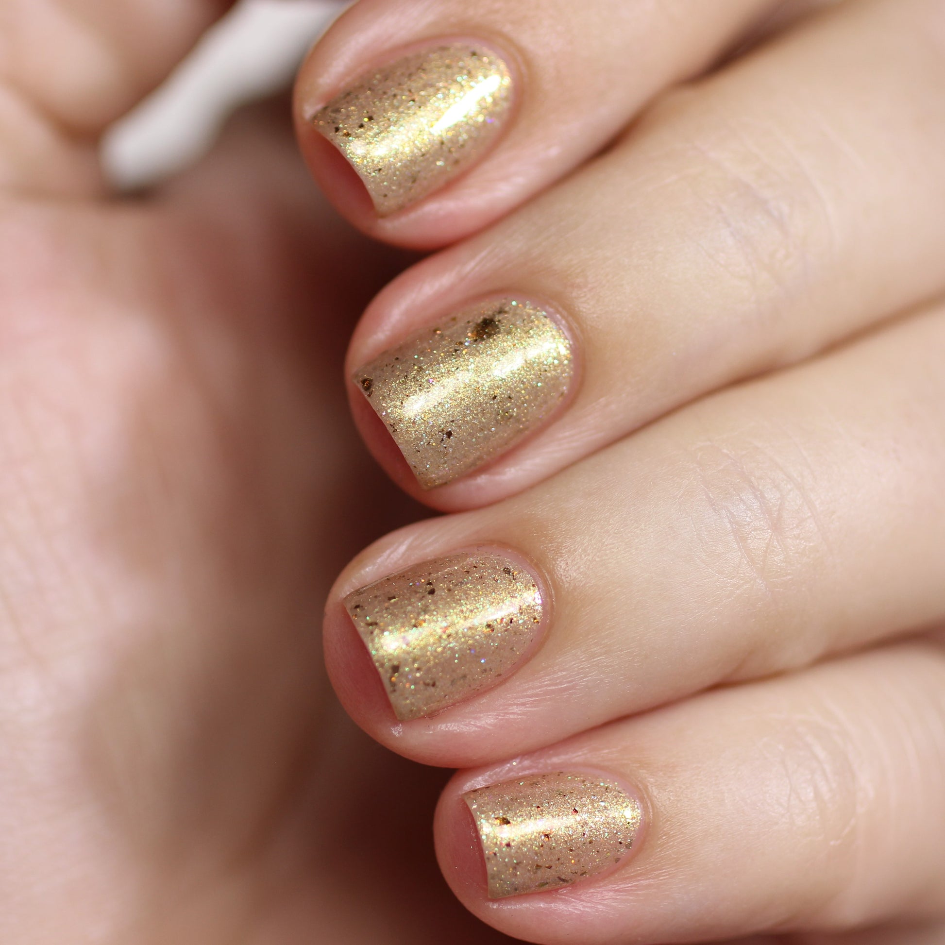 A detailed view of a hand adorned with neatly manicured nails, painted in Golden King.001 Gold Nail Polish by PI Colors, showcasing the elegance of luxurious nail lacquers.