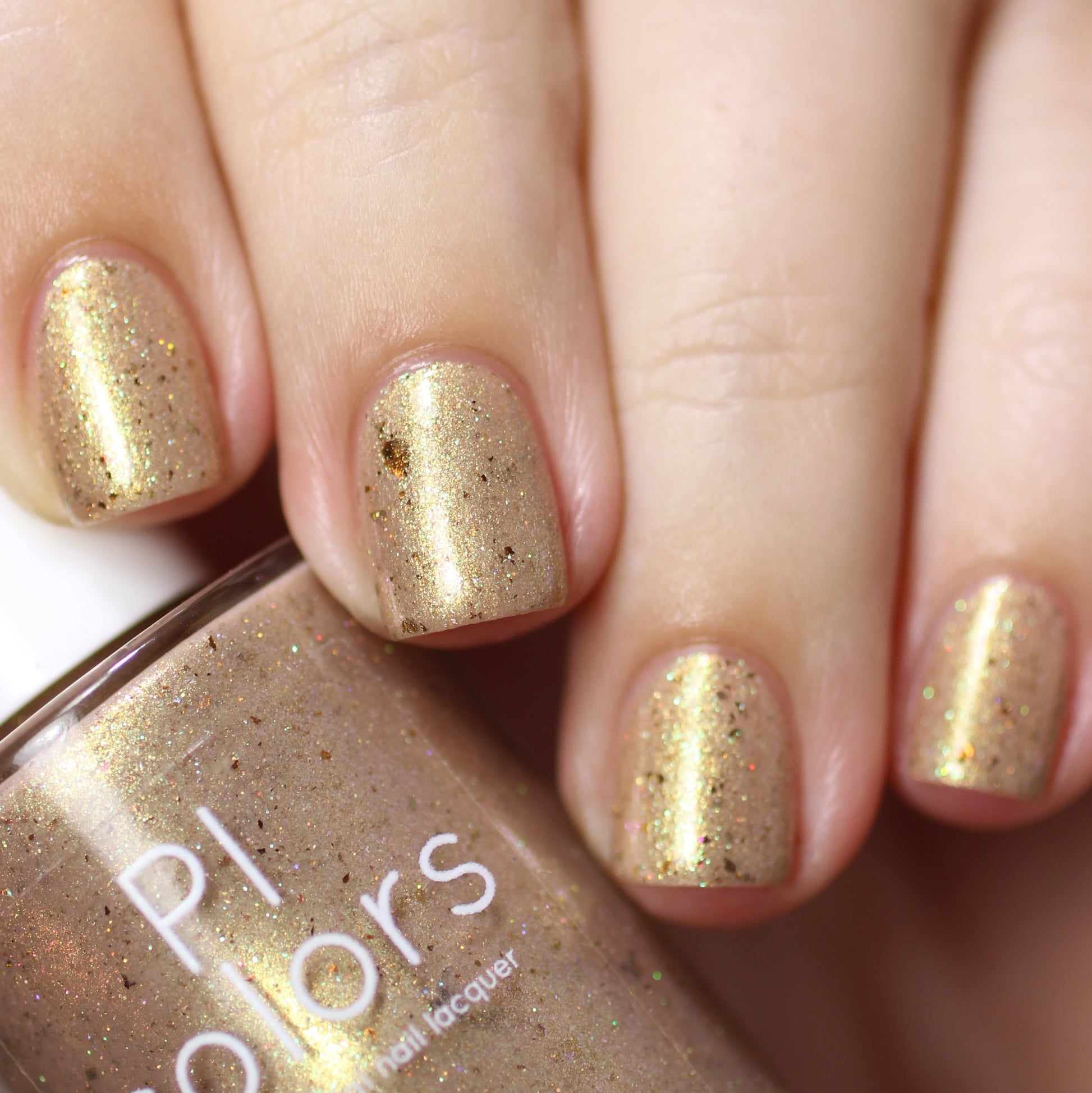 A close-up shot features a hand with neatly manicured nails painted in a luxurious gold glitter polish. The "Golden King.001 Gold Nail Polish" by PI Colors bottle matches the holographic glitter hue, showcasing a sparkly golden finish.