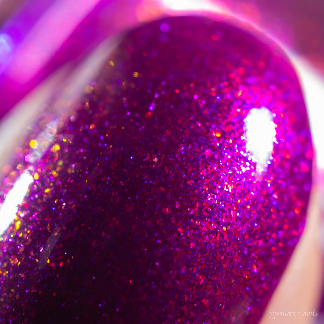 Close-up of a fingernail painted with PI Colors Aubergine.100, a vibrant magenta luxury nail lacquer that shimmers with red, deep purple, and gold under bright light.