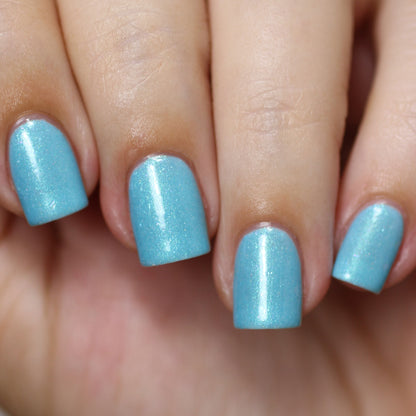 A close-up captures the light blue, subtly shimmering nails of a hand, perfectly manicured with the Berry Mousse.001 Blue Nail Polish by PI Colors. The neatly coated nails gracefully reflect light, highlighting the elegance of its 10-free formula.