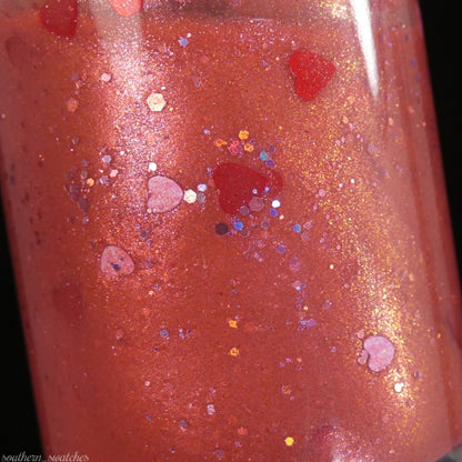 Close-up of a luxury Strawberry Jam.228 Red Nail Polish bottle by PI Colors, showcasing its shimmering red hue. The lacquer is infused with colorful heart-shaped and circular glitter, reflecting light in various shades. Its glossy surface highlights an ornate and sparkling design, exuding elegance and charm.