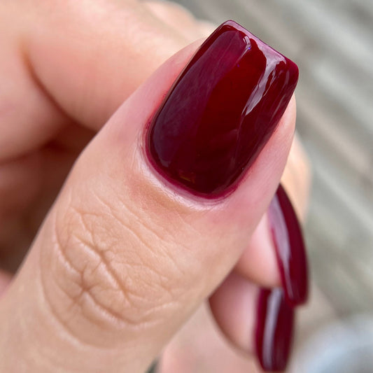 Close-up of a hand with dark red nail polish on a blurred background