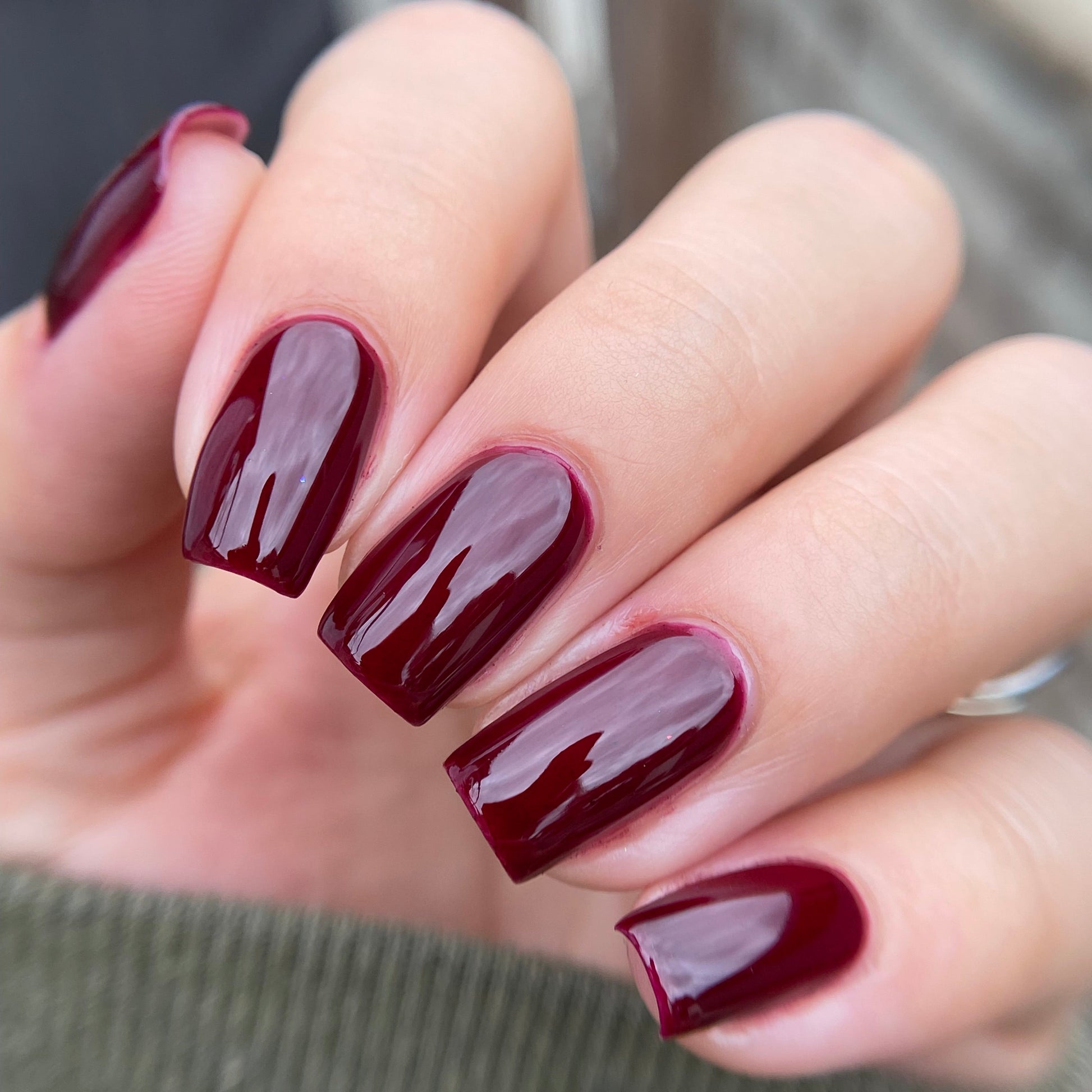 Close-up of a hand with burgundy nail polish on a blurred background