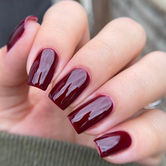 Close-up of a hand with burgundy nail polish on a blurred background