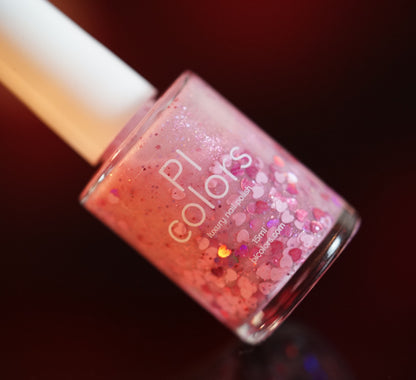 A close-up of a "Pink Berry Heart.200" by PI Colors shows a pale pink polish with glitter in various sizes. Holographic hearts add whimsy, complemented by a blurred red and orange gradient background that enhances the sparkle.