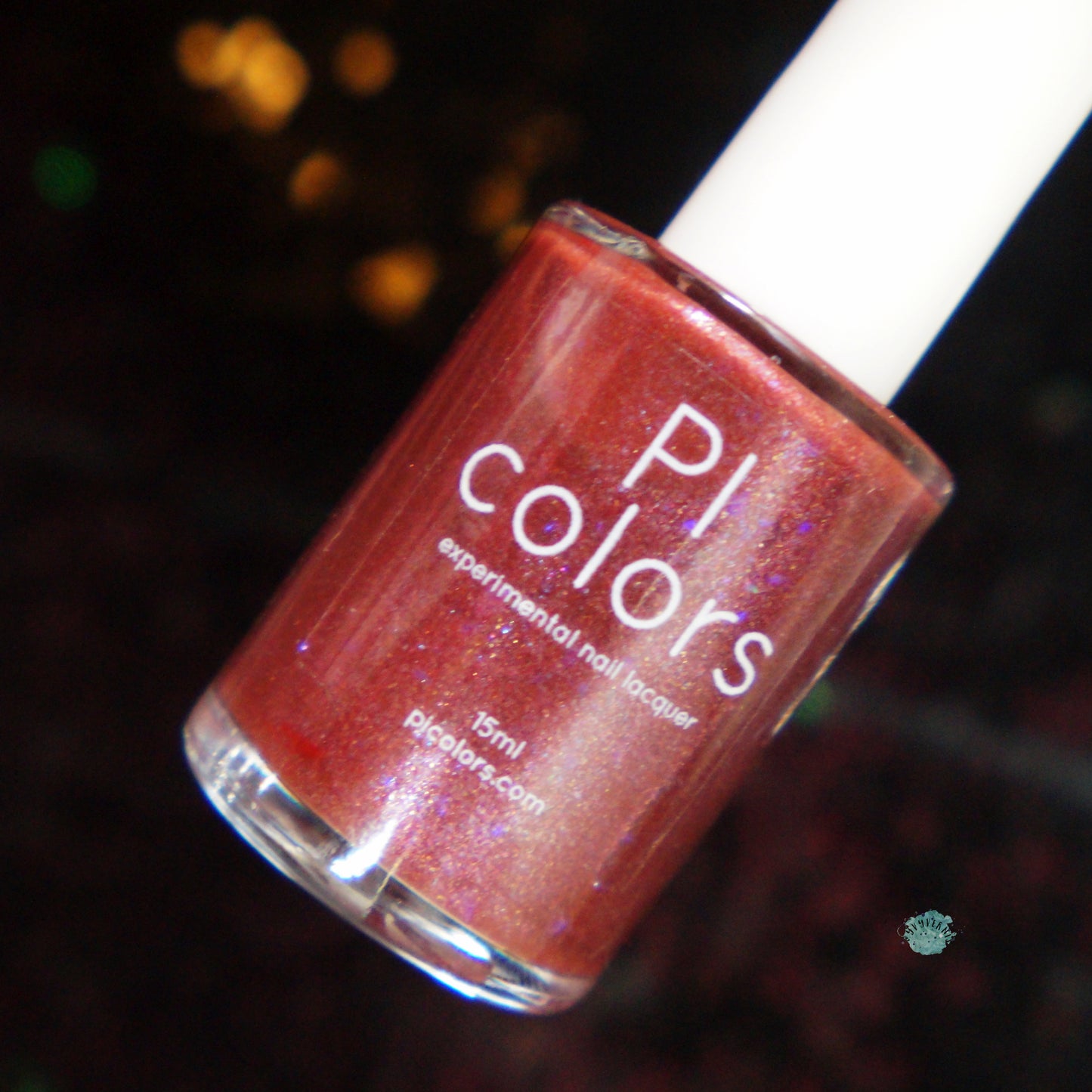 A bottle of PI Colors Quasar.156 Red Nail Polish featuring a shimmering red hue with color-shifting flakies, set against a softly blurred dark background. The bottle is labeled with the brand name and website.