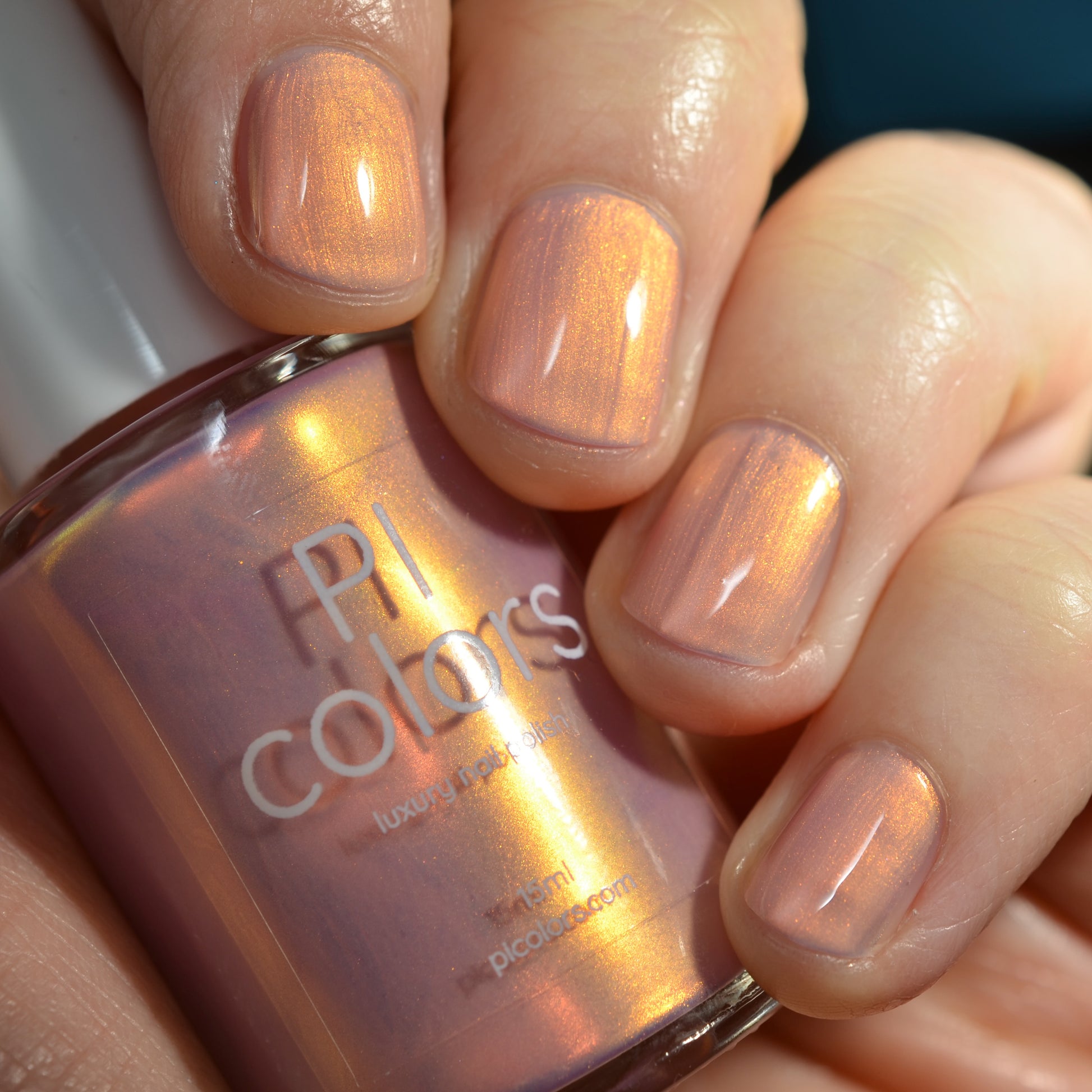 Hand holding a bottle of PI Colors nail polish with matching nails.