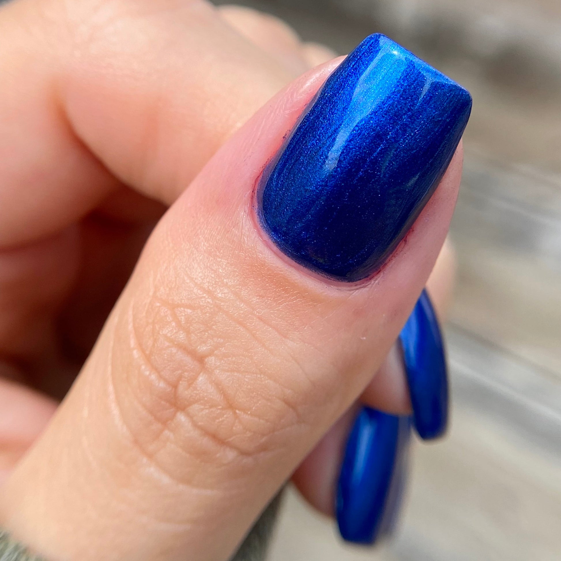 Close-up of a hand with blue nail polish on a blurred background